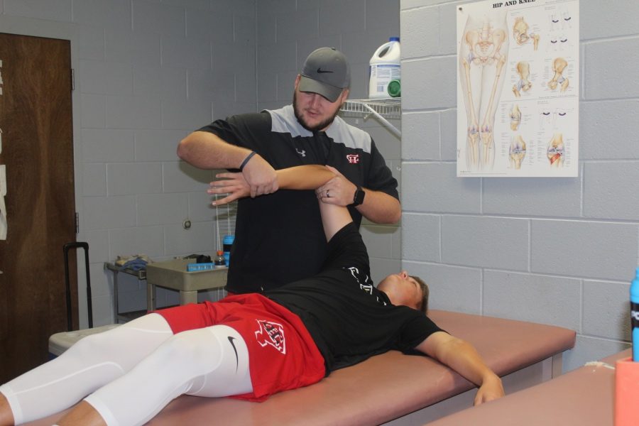 Athletic trainer Phil Weivoda helps baseball player Zach Wright stretch his shoulder. Wright, a right handed pitcher and outfielder for the Mustangs, had surgery in July.