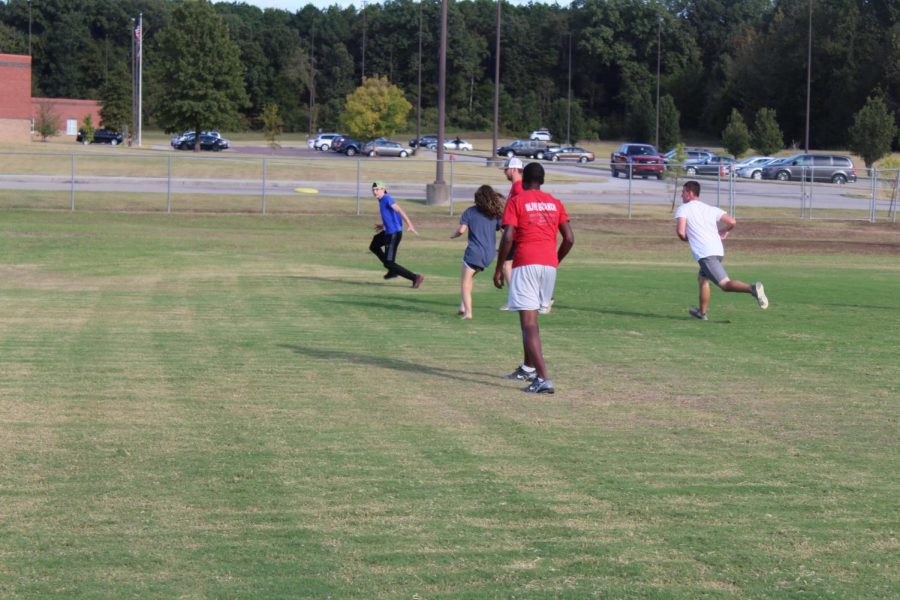 Trey Stuard, far left, runs to catch a flying disc at Ultimate practice. Stuard, senior captain of the Ultimate team, has played all four years of high school and described the non-contact sport as “kind of like football.”