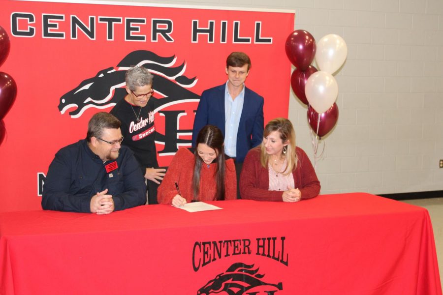 Maggie+Gaines+signed+today+to+play+soccer+at+Hinds+Community+College.+She+is+seated+with+her+father%2C+Tim+Gaines%2C+and+her+mother%2C+Rachel+Robertson.+Standing+from+left+are+Assistant+Principal+Brenda+Case+and+head+girls+soccer+coach+Ryan+Worsham.