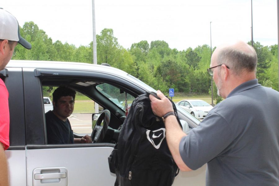 Bill Hatch hands Gus Lockett the contents of Locketts locker on April 28, the first of two drive-thru locker clean out days at CHHS for seniors. Seniors will also be able to return library books and textbooks on April 30. There will be designated times for all students to drop off books and retrieve personal items May 4-8.