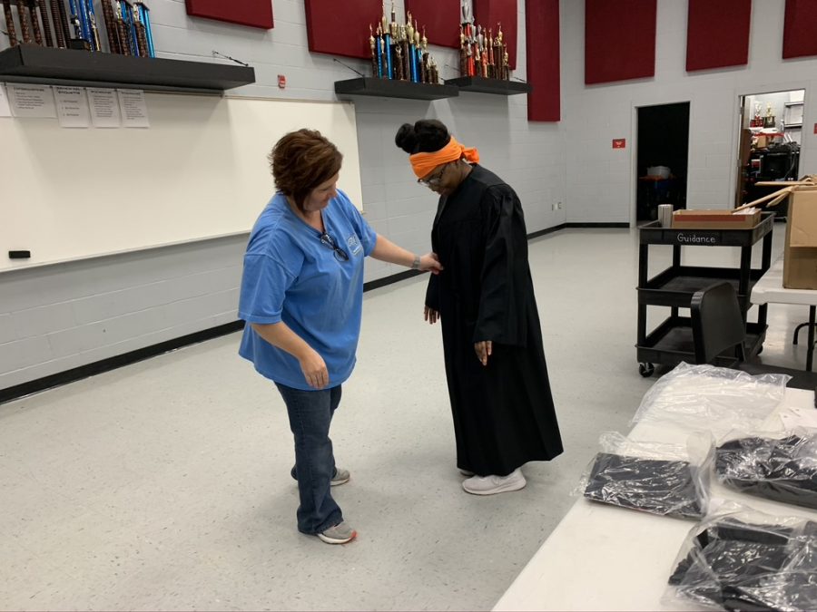 Cathy Dawson helps Shamyra Thomas try on her cap and gown June 2. Thomas said with a family of 10, the limit of six people at her graduation ceremony is going to be hard.