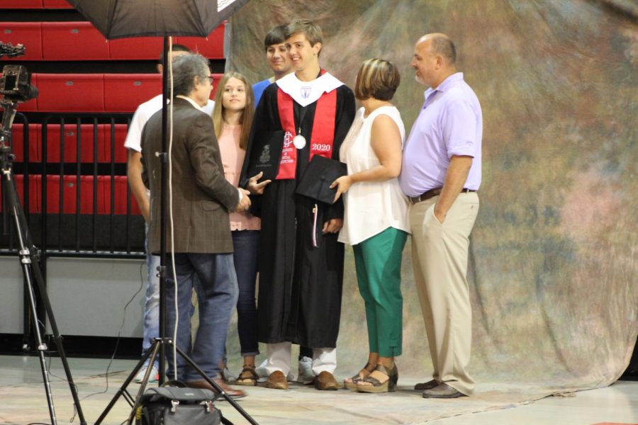 Surrounded by his family, Dru Hines prepares to have graduation pictures taken by a Holland Studio photographer. Hines graduated with special distinction June 9 in a ceremony that followed CDC guidelines.